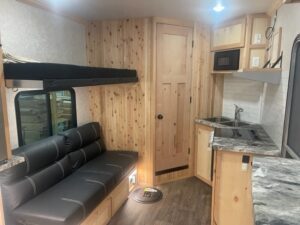 Nordic Loge kitchen area with black love seat, a sink, and stove with grey marble counter tops.