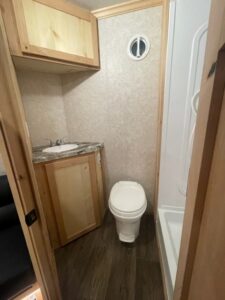 Nordic Lodge fish house bathroom with tan walls and a wooden accent and a white sink, toilet, and shower