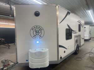Nordic Lodge logo on the white exterior of a Nordic Lodge fish house with black and grey markings