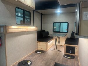 Interior of fish house camper's dining space. Black love seats on both sides of a grey marble table
