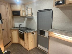 Fish house kitchen area with a sink, and stove with grey marble counter tops.